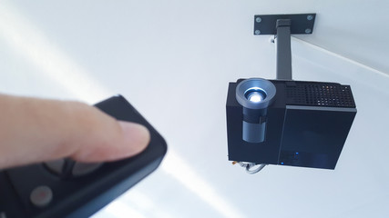 hand turning on the projector from the remote control in the meeting room