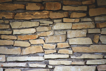 part of the wall is made up of individual pieces of stones in cement, the dark upper part is gradually lighter down, yellow and brown shades,
