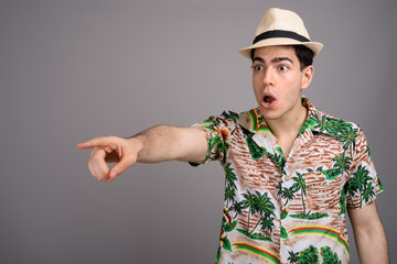 Young handsome tourist man ready for vacation against gray backg