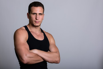 Studio shot of young muscular Persian man with arms crossed agai