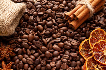 Coffee beans scattered on the table, with cinnamon, anise stars and dried orange. For packages of coffee, for the menu in coffee houses. Concept idea for design.