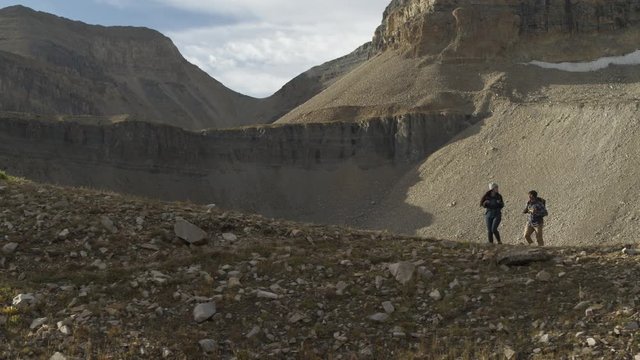 Panning shot of couple climbing hill in mountain range / Mount Timpanogos, Utah, United States