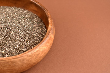 Chia seeds stock images. Healthy food isolated on a brown background. Chia seeds in a wooden bowl