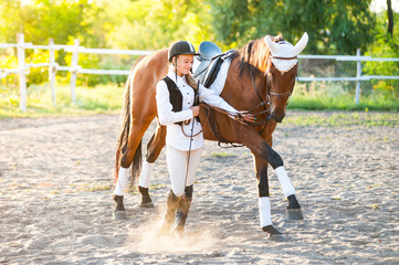 Girl equestrian rider riding a beautiful horse  in the rays of the setting sun.
