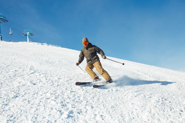 Naklejka na ściany i meble Nice man skiing in the mountains. Good skiing in the snowy mountains, Winter is coming, first snowfall. Ski resort season is open. Ski equipment, trail. 