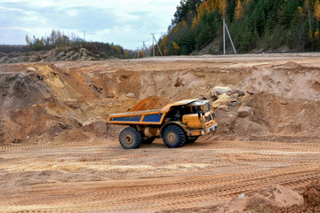 Earth mover loading dumper truck with sand in quarry. Excavator loading sand into dumper truck.Quarry for the extraction of minerals. Large quarry dump truck. Production useful minerals.