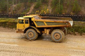 Obraz premium Earth mover loading dumper truck with sand in quarry. Excavator loading sand into dumper truck.Quarry for the extraction of minerals. Large quarry dump truck. Production useful minerals.