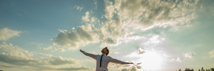 Wide view image of businessman standing under majestic sky