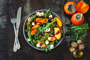 Healthy salad with persimmon, arugula, nuts and feta cheese. Fitness food. Superfoods Vitamin autumn persimmon salad.