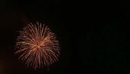 Gold starburst with hints of green and red throughout against a black background on the Fourth of July