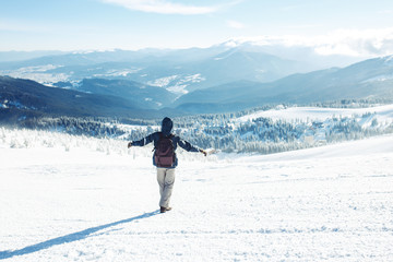 Fototapeta na wymiar Man with backpack trekking in mountains. Cold weather, snow on hills. Winter hiking. Winter is coming, first snowfall. concept of travel, rest, relaxation
