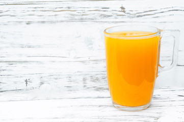 A glass of orange juice on a white wooden background