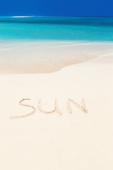 Handwritting inscription word SUN on sandy beach