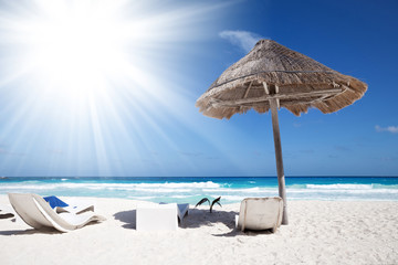 Sun umbrella with wooden lounge chairs on tropical shore