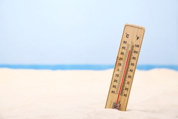 Thermometer buried in the sand showing high temperature at the beach