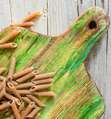 Wholemeal pasta on green rustic wooden chopping board