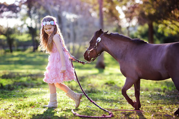 Cute little girl and pony in a beautiful park