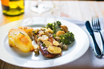 Grilled tilapia whitefish fillet with lemon zest sauce, hand cut roasted potato wedges and sauteed brocolis and mushrooms. Saint Peter, latin term Pseudocrenilabrinae. Bottle and glass of white wine