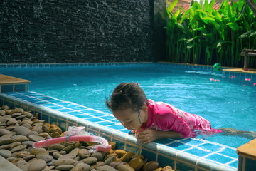 Cute girl playing pool with fun.Cute girl is playing in the pool.Outdoor Swimming Pool.