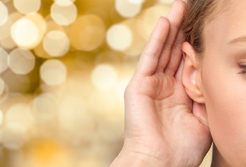 Girl listening with her hand on an ear cose up