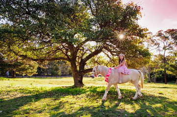 Cute little girl and pony in a beautiful park