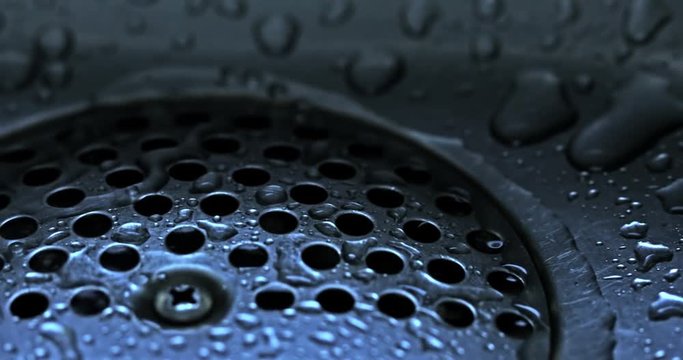 Close up on dripping water from faucet in a kitchen sink. Close up, dolly used for camera movement. 4K.