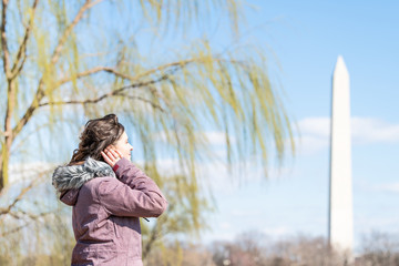Closeup of young female, woman profile, face looking at view on Washington Monument with willow tree branches, green leaves, foliage in spring, blue sky