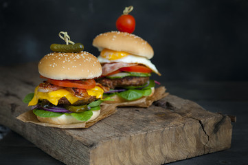  Two hamburgers and french fries on brown paper . hamburgers with meat, cheese, onion and salad 