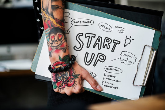 Tattooed hand holding a startup clipboard