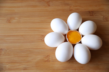 organic eggs on a wooden background folded in the form of a chamomile with a yolk in the center. Top view. Flat lay. Copy space for text.