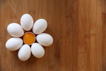 white eggs laid out in the form of a flower with a yolk in the center on a bamboo background. With copy space for text. Flat lay. Top view. Easter.