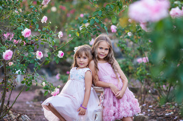 Beautiful children on a girls party in a blooming rose garden