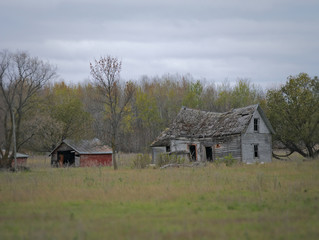 Drab Abandoned Dilapidated Farm House and Shed with clouds in northern Minnesota