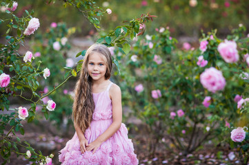Beautiful children on a girls party in a blooming rose garden