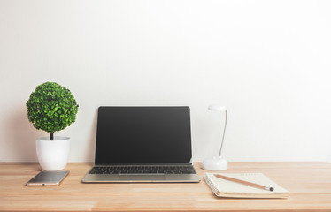 Fototapeta premium Artificial tree with notebook laptop mobile phone and pencil on work desk.