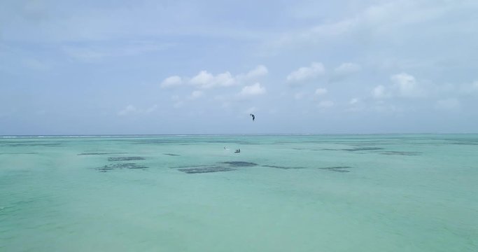 Wide aerial, people parasail in tropical ocean