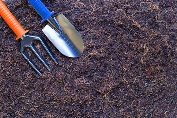Garden shovel and fork on soil with coconut shell's hair for agriculture.