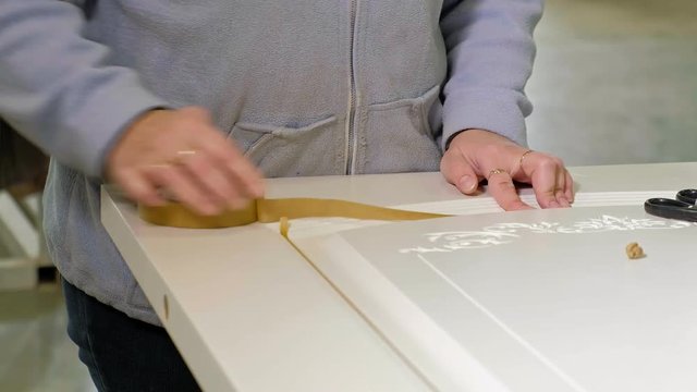 woman glues adhesive tape. production of interior doors of wood