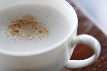 
White cup of hot coffee on the wooden table, soft focus , blurred.