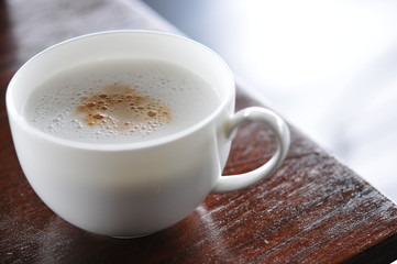 
White cup of hot coffee on the wooden table, soft focus , blurred.