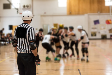 Roller derby referee watches teams for penalties