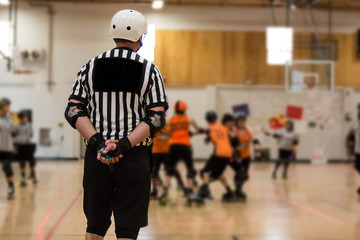 Roller derby referee watches teams for penalties