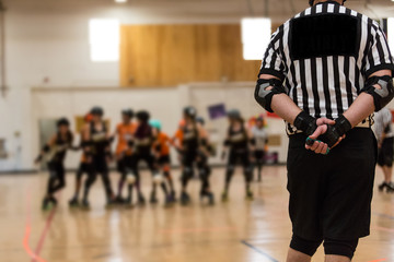 Roller derby referee watches teams for penalties