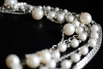 Necklace of white beads and metal chain on a dark background close up