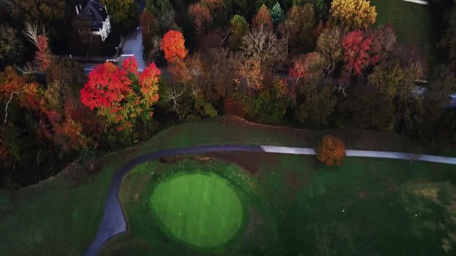Flying above the stunning colorful treetops and golf course in Louisville with leaves turning colors on sunny morning. Beautiful autumn trees in yellow, orange and red forest on sunny autumn day. Fall