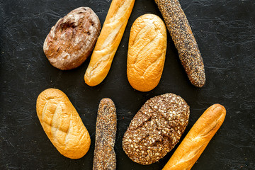 Set of fresh homemade bread. Bread assortment. Loaf, baguette. White and brown bread on black background top view