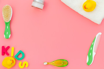 Hygiene items for the child. Bath accessories with yellow rubber duck on pink background top view copy space frame. Word KIDS