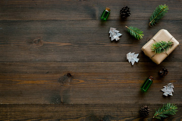 Background with New Year gift. Box wrapped in craft paper, decorated with pine sprig and cones on dark wooden background top view copy space