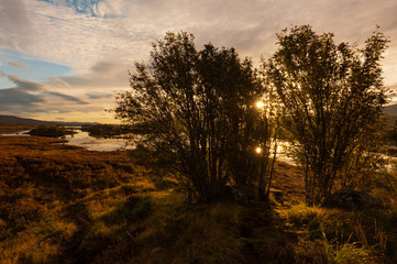 Dawn sun reflected in lake making double sunburst on Scottish loch in Glencoe