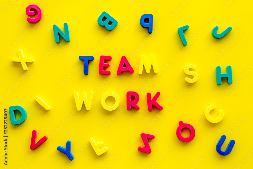 Poster teamwork training concept. text teamwork lined with colored letters in frame of toy letters on yello